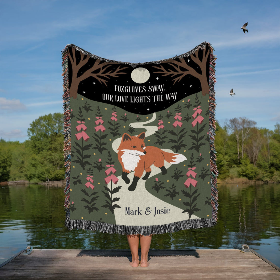 Person holding a blanket with a fox design by a lake