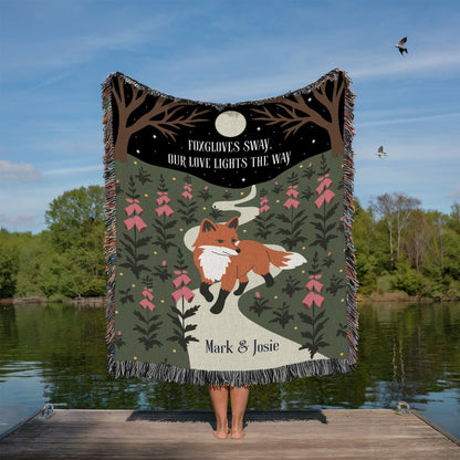 Person holding a blanket with a fox design by a lake