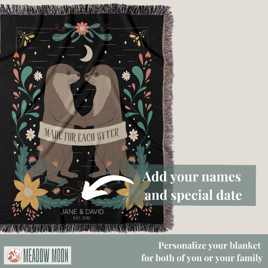 Blanket with two otters holding hands and floral design, featuring text 'Made for each other' and 'Meadow Moon' branding.